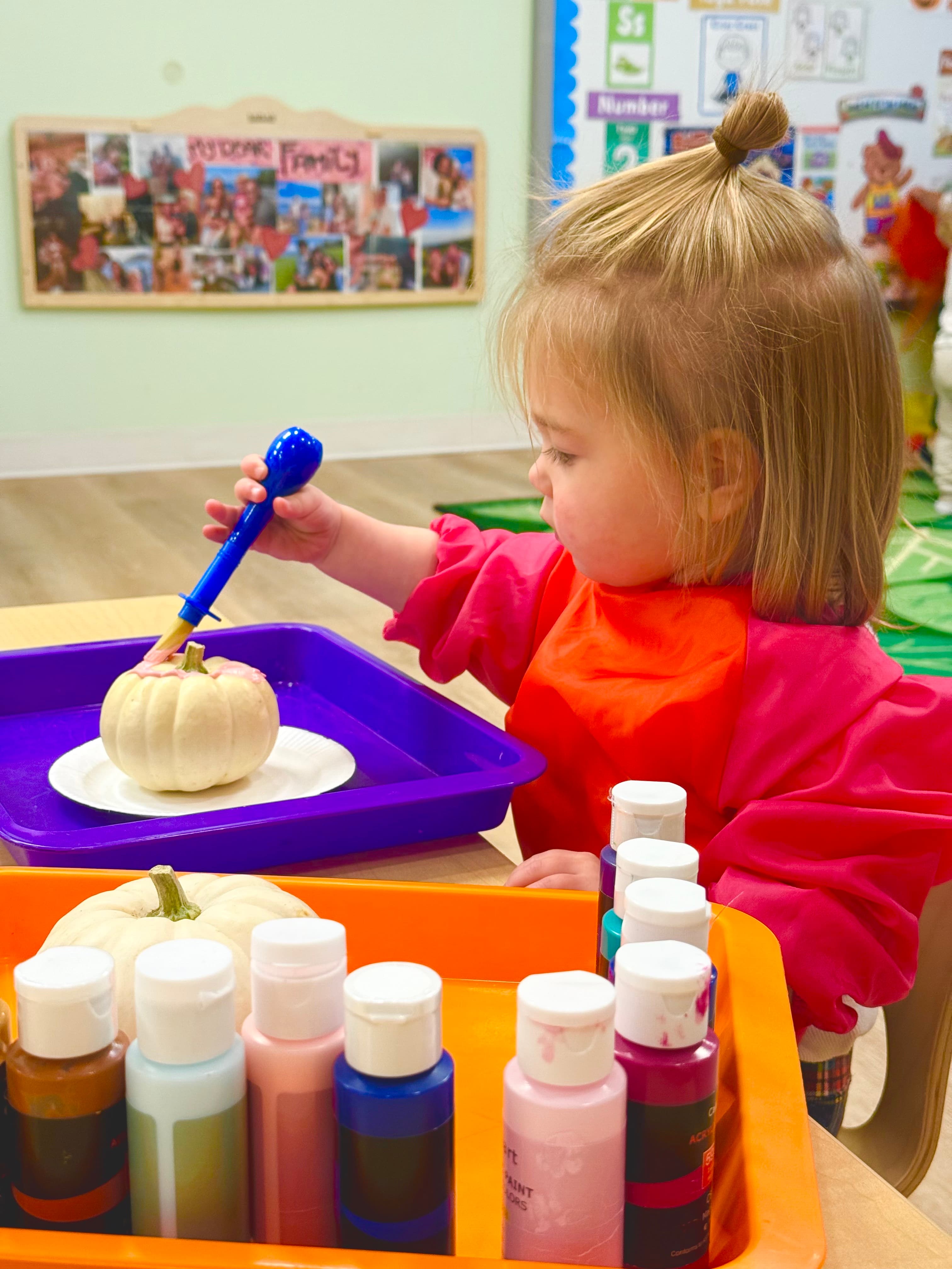 Child painting a pumpkin during a fall classroom activity