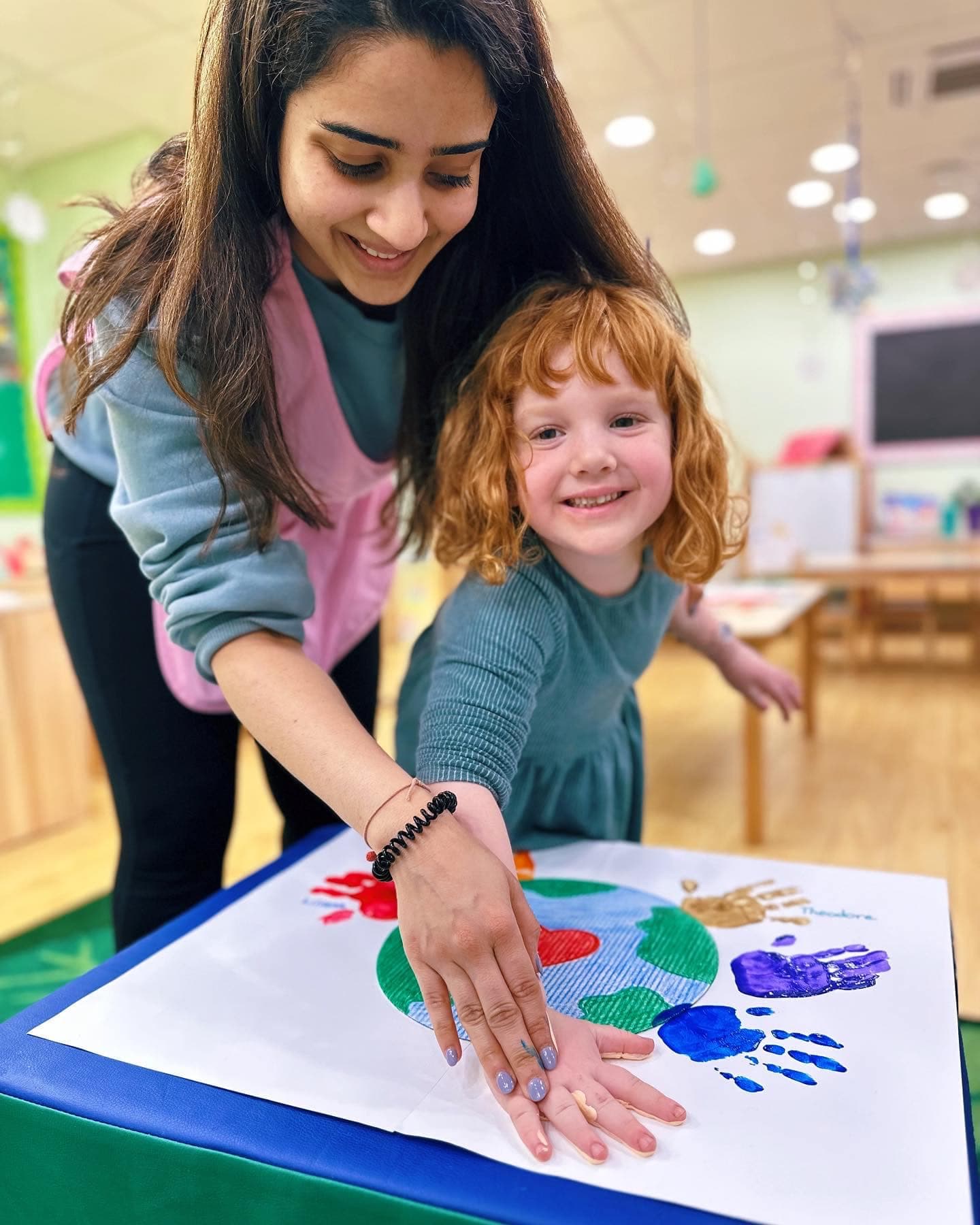 Teacher helping child with handprint art project