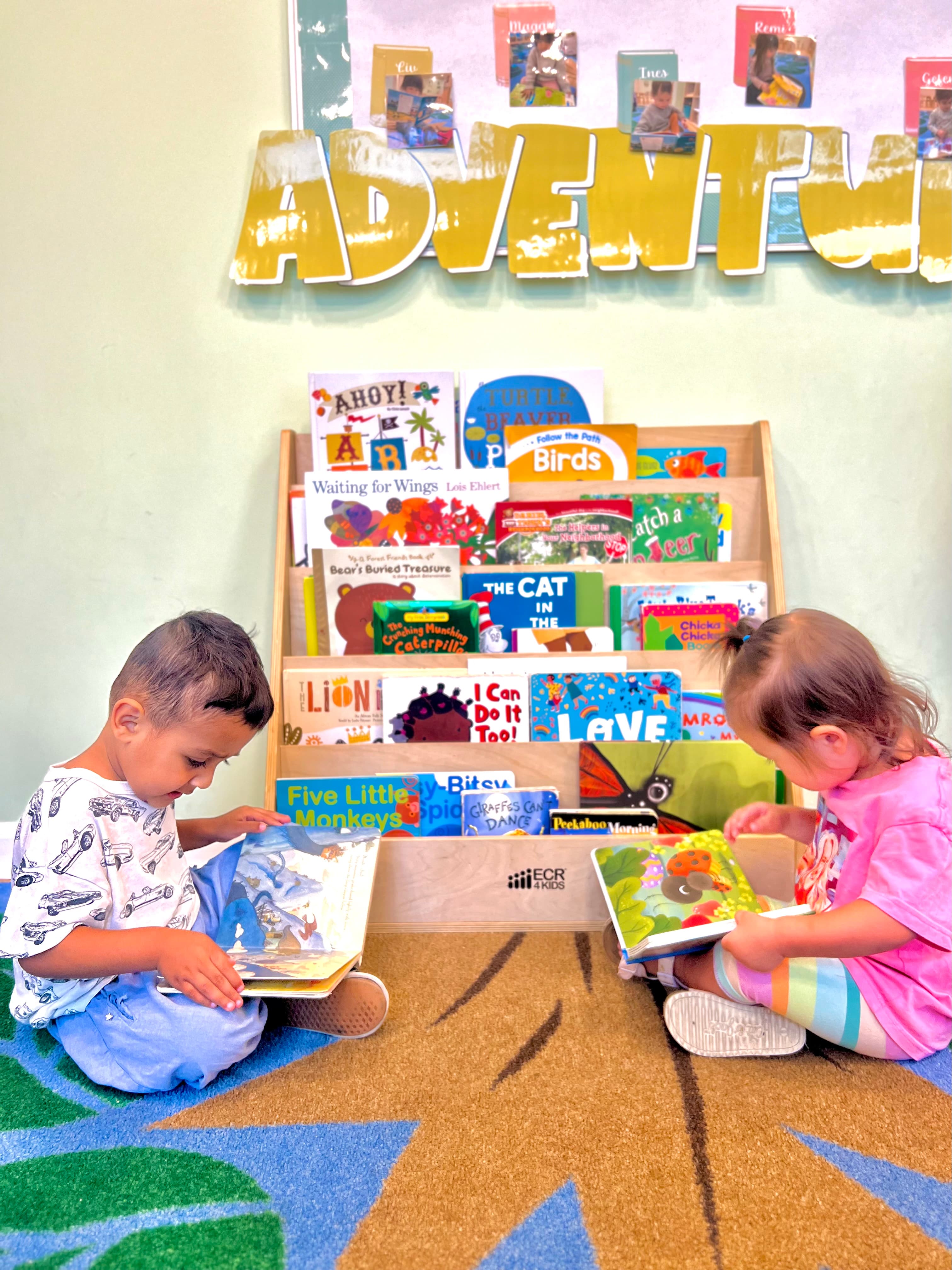 Two children reading board books in the classroom book nook